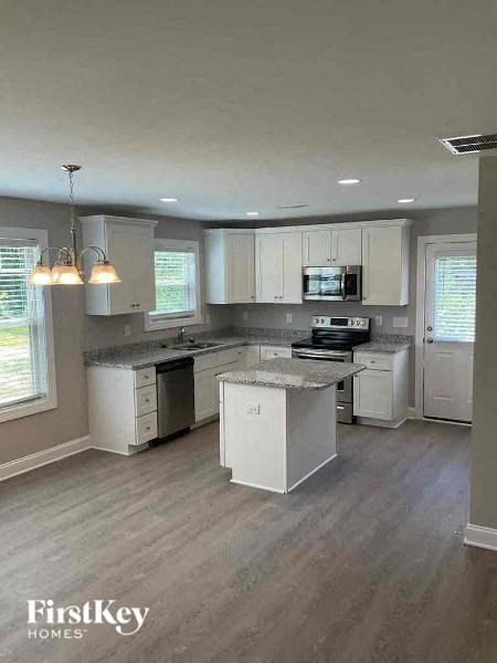 an empty kitchen with white cabinets and stainless steel appliances
