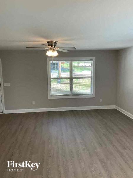 an empty bedroom with a ceiling fan and a window