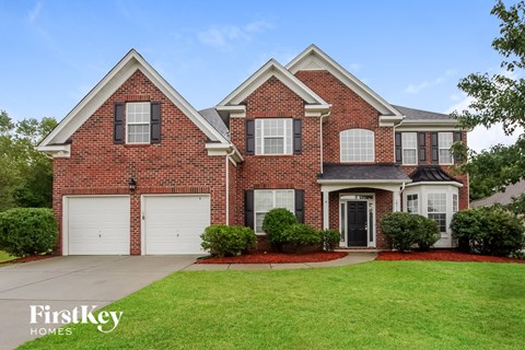 a brick house with white garage doors and a lawn