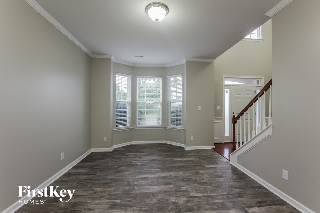 an empty living room with a staircase and windows
