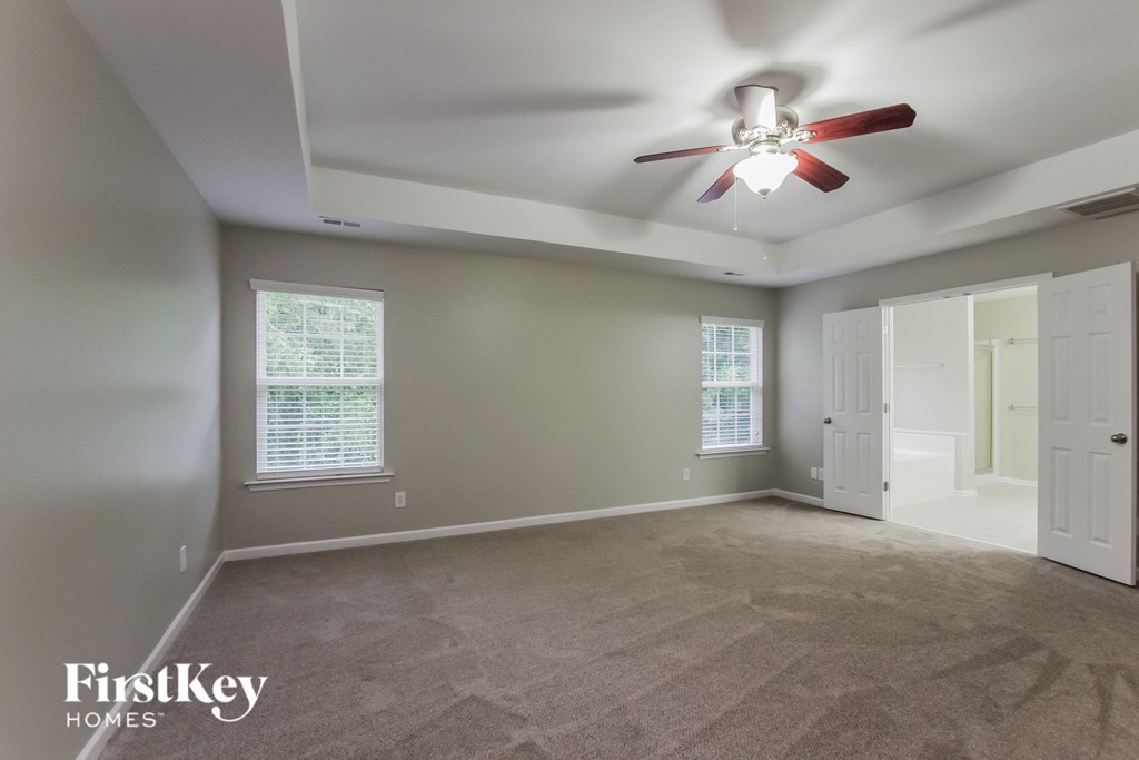 an empty living room with a ceiling fan and a white door