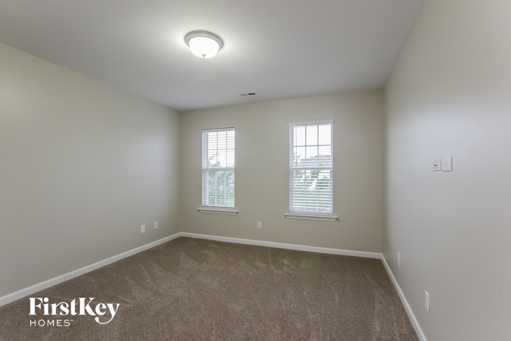 a bedroom with a carpeted floor and two windows