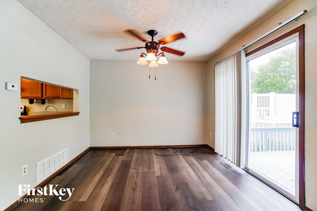 the living room with wood flooring and a ceiling fan