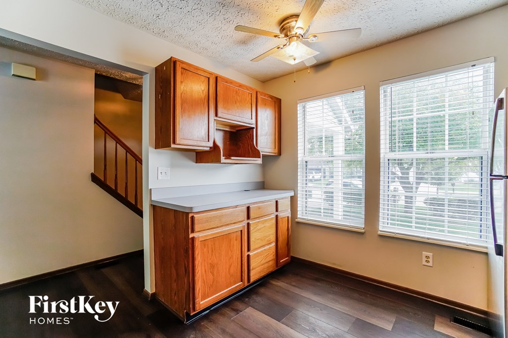 an empty kitchen with a ceiling fan and a staircase