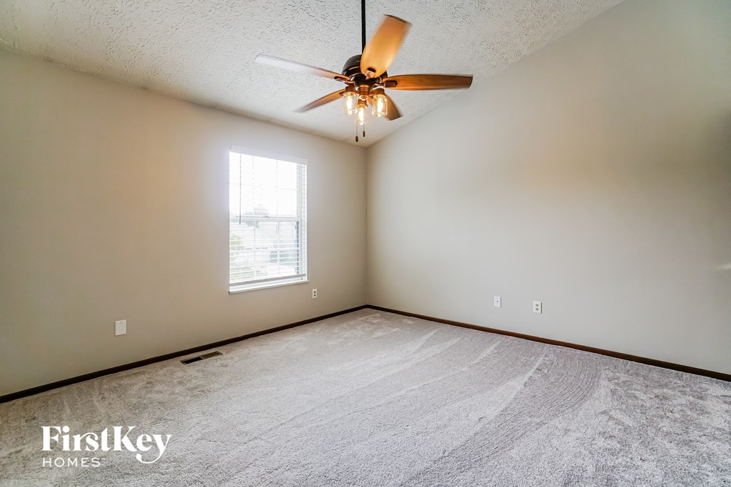 the living room is spacious and has a ceiling fan