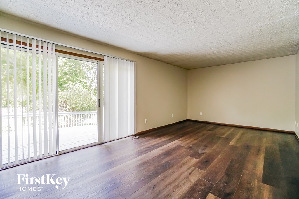 an empty living room with wood flooring and sliding glass doors