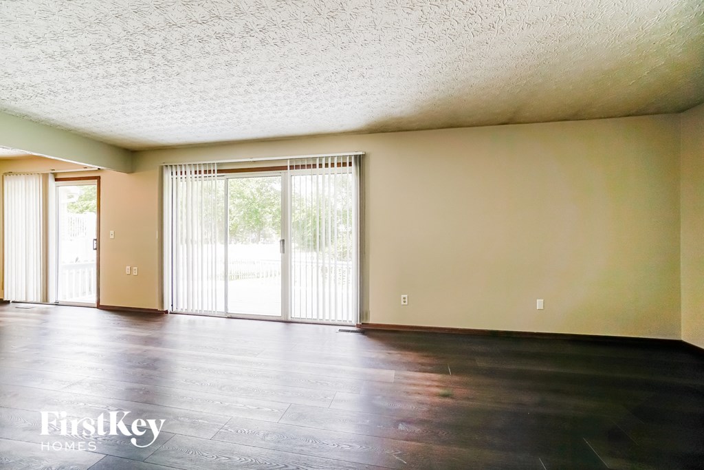 an empty living room with hard wood floors and sliding glass doors