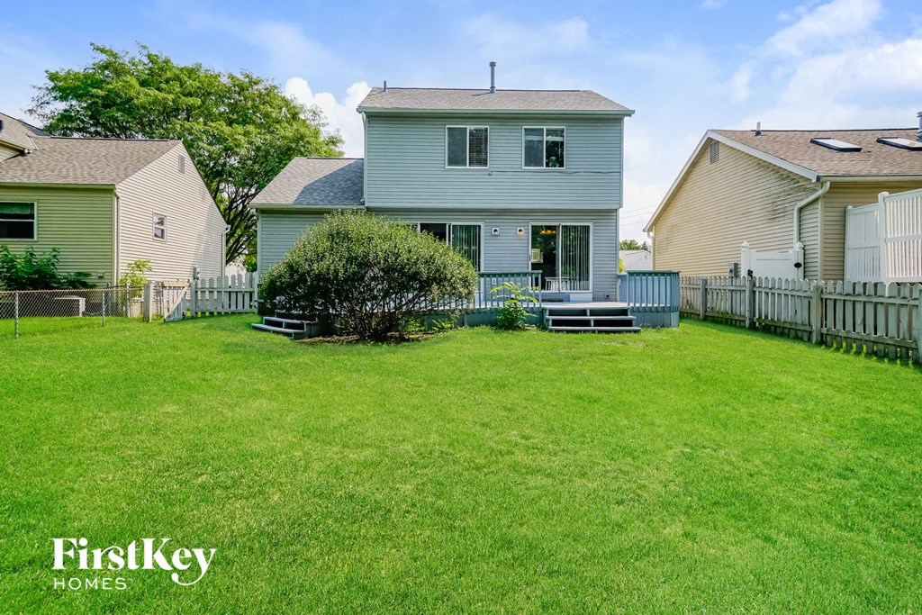 a backyard with a blue house and a white fence