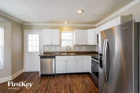 A kitchen with a stainless steel refrigerator and wooden floors.