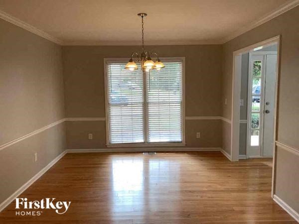 A room with wooden floors and a chandelier hanging from the ceiling.