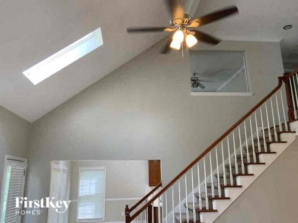 A staircase with a wooden handrail and a ceiling fan with lights.