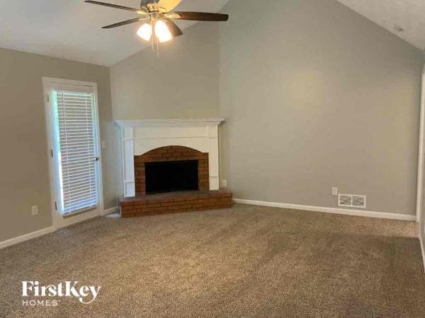 A living room with a fireplace and a ceiling fan.