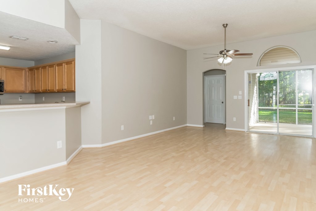 A spacious room with wooden flooring and a ceiling fan.