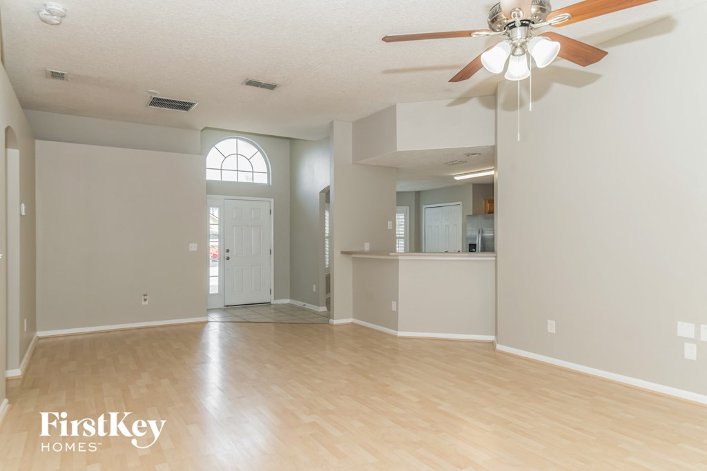 A spacious room with a ceiling fan and light fixture.