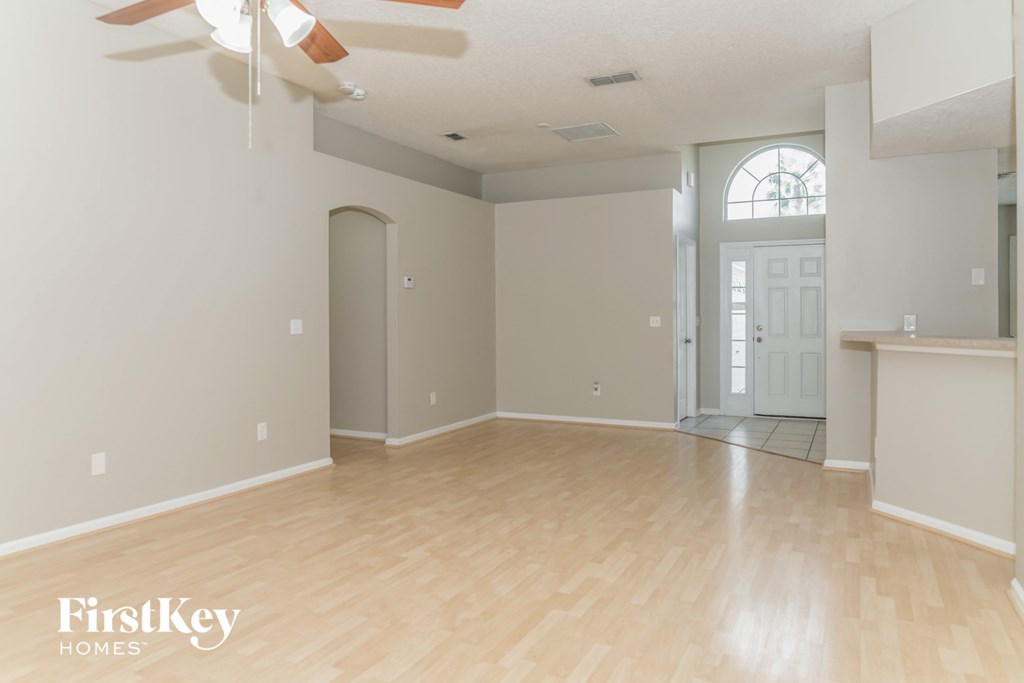 A spacious room with a fan and wooden flooring.
