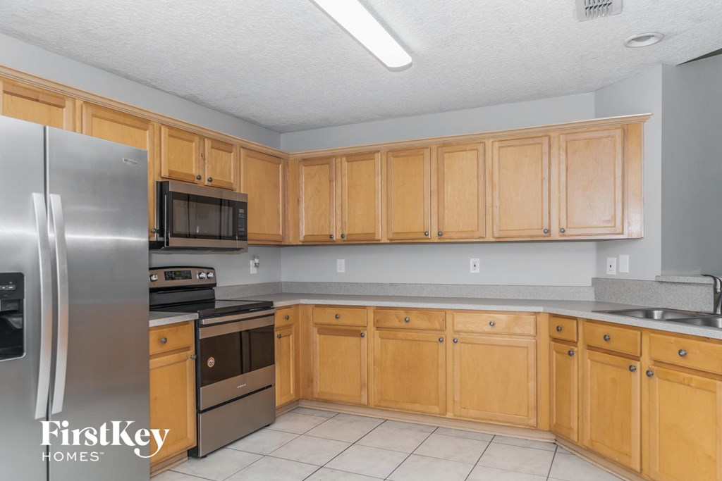 A kitchen with wooden cabinets and a stainless steel refrigerator.