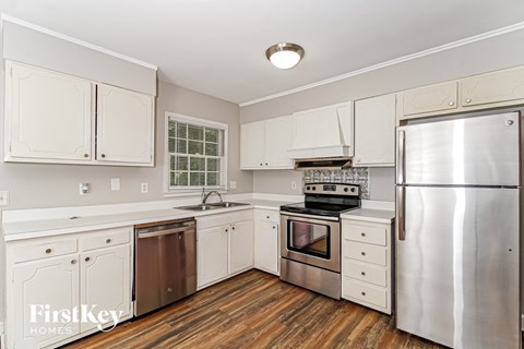 A kitchen with white cabinets and a stainless steel refrigerator.