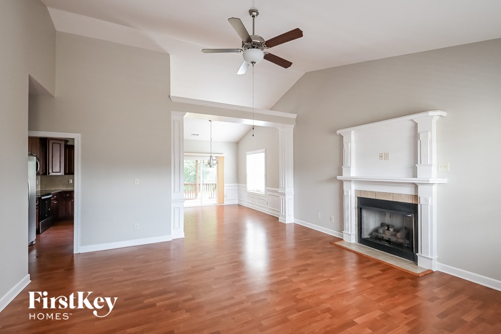 an empty living room with a fireplace and a ceiling fan