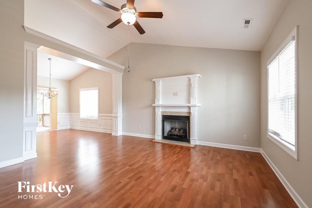 an empty living room with a fireplace and a ceiling fan