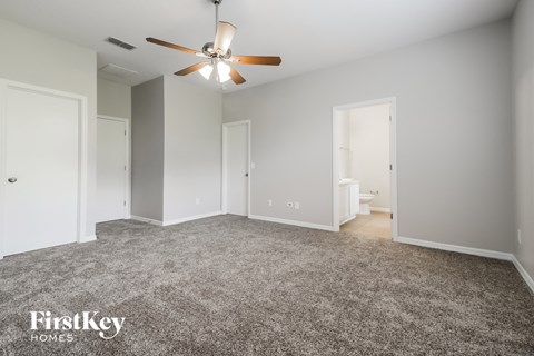 a spacious living room with gray carpet and a ceiling fan