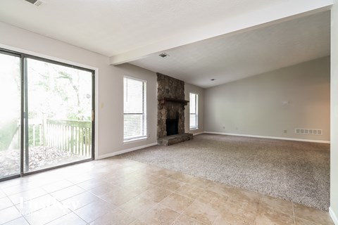 an empty living room with a fireplace and sliding glass doors