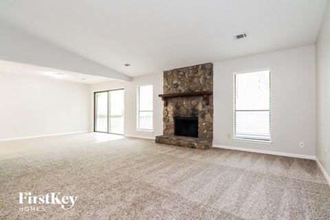 a spacious living room with a fireplace and carpeted flooring
