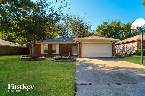 a small brick house with a basketball hoop on the driveway