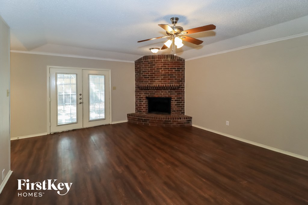 the living room of a house with a fireplace and a ceiling fan