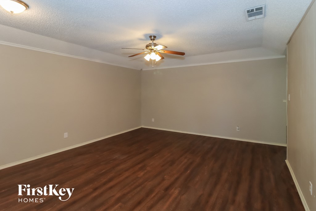 the living room of an empty house with wooden floors and a ceiling fan