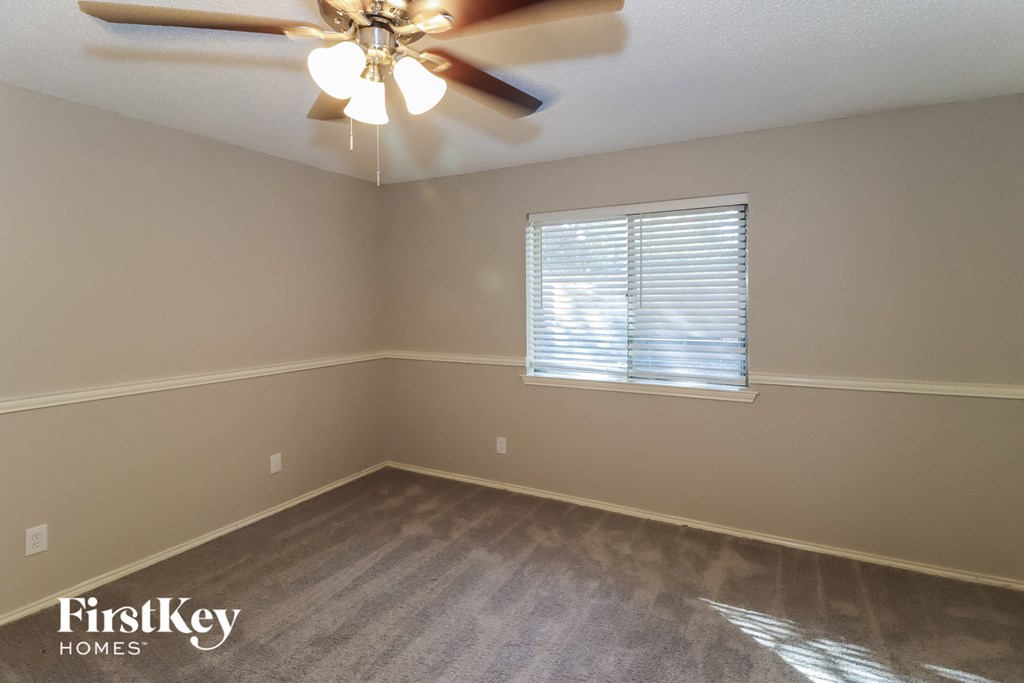 an empty room with a ceiling fan and a window
