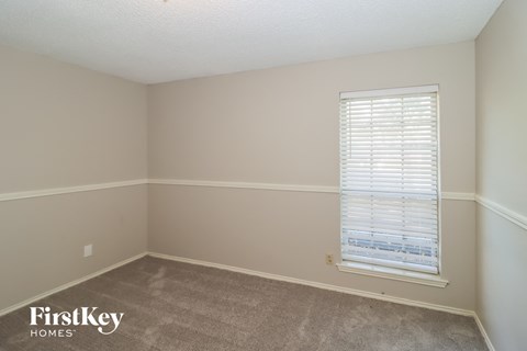 a bedroom with a window and a carpeted floor