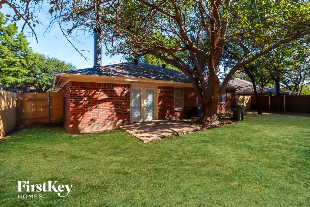 a small red brick house with a tree in the yard