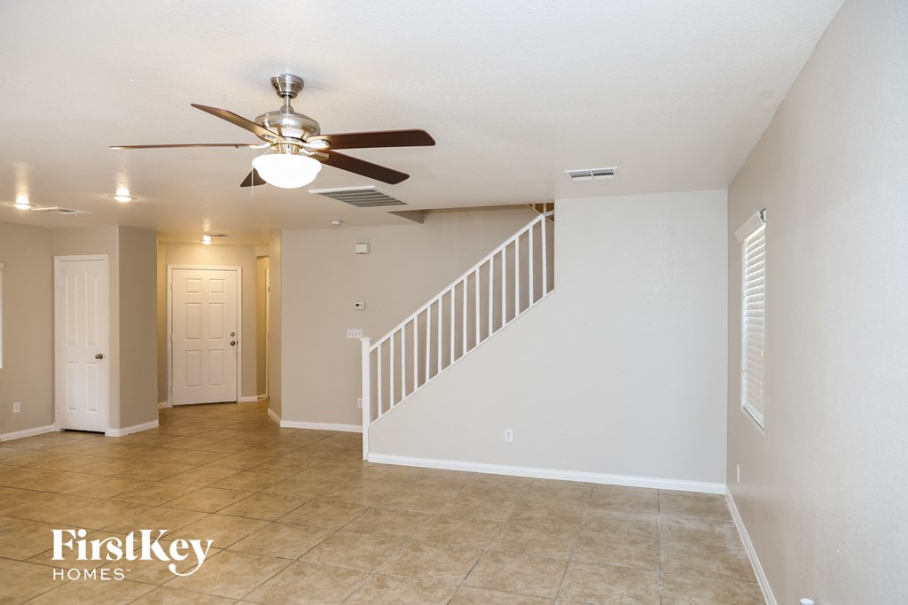 A spacious room with a staircase and a ceiling fan.