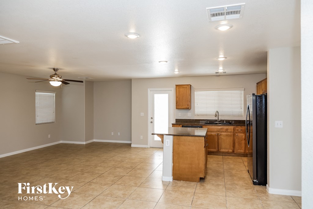 A kitchen area with a refrigerator, sink, and cabinets.