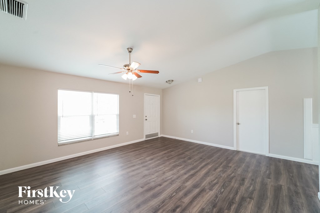 A spacious room with wooden flooring and a ceiling fan.