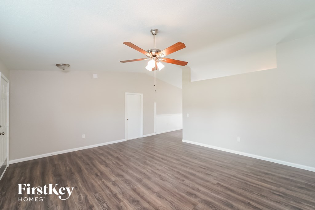 A room with a ceiling fan and wooden flooring.