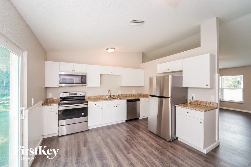 A kitchen with white cabinets and a stainless steel refrigerator.