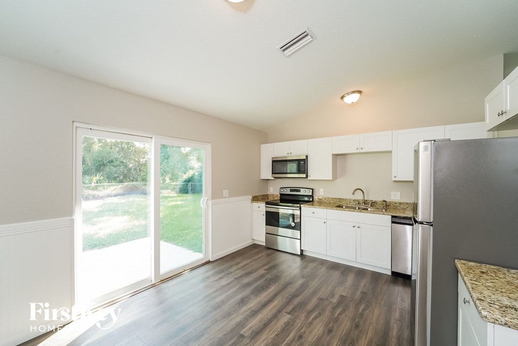 A kitchen with white cabinets and a refrigerator.