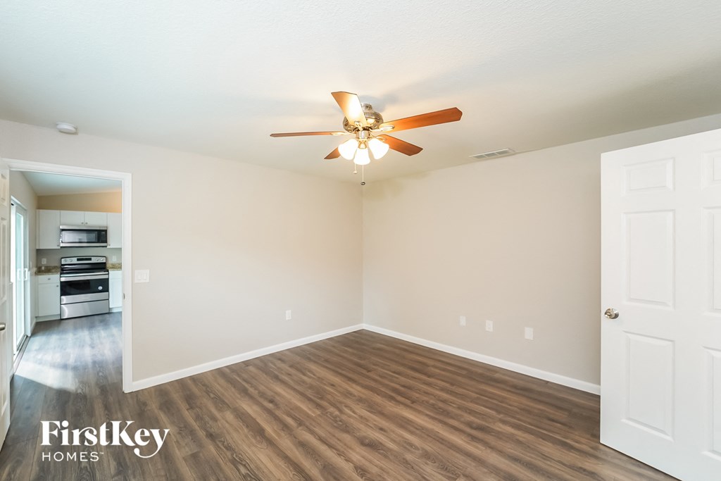 A room with a ceiling fan and wooden flooring.