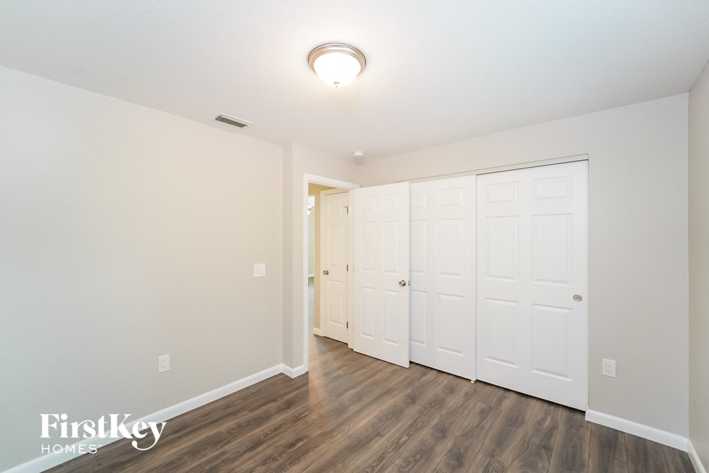 A room with a white ceiling and wooden floors with a FirstKey Homes logo.