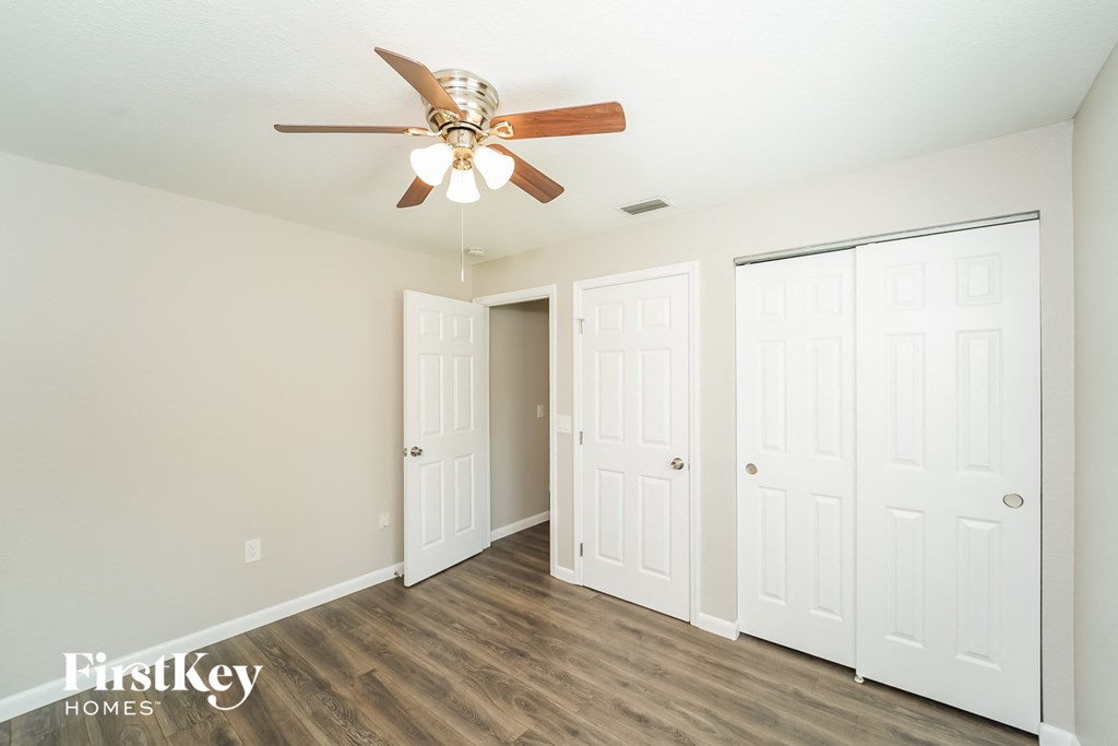 A room with a ceiling fan and three doors.