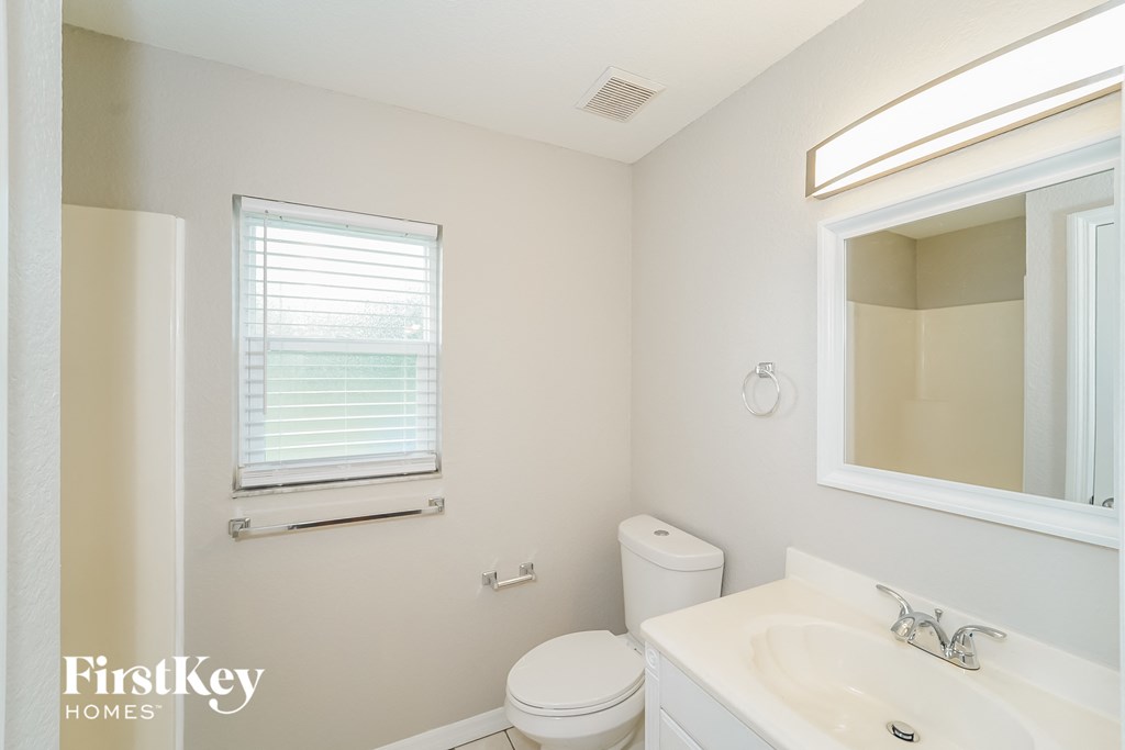 A white bathroom with a toilet, sink, and window.