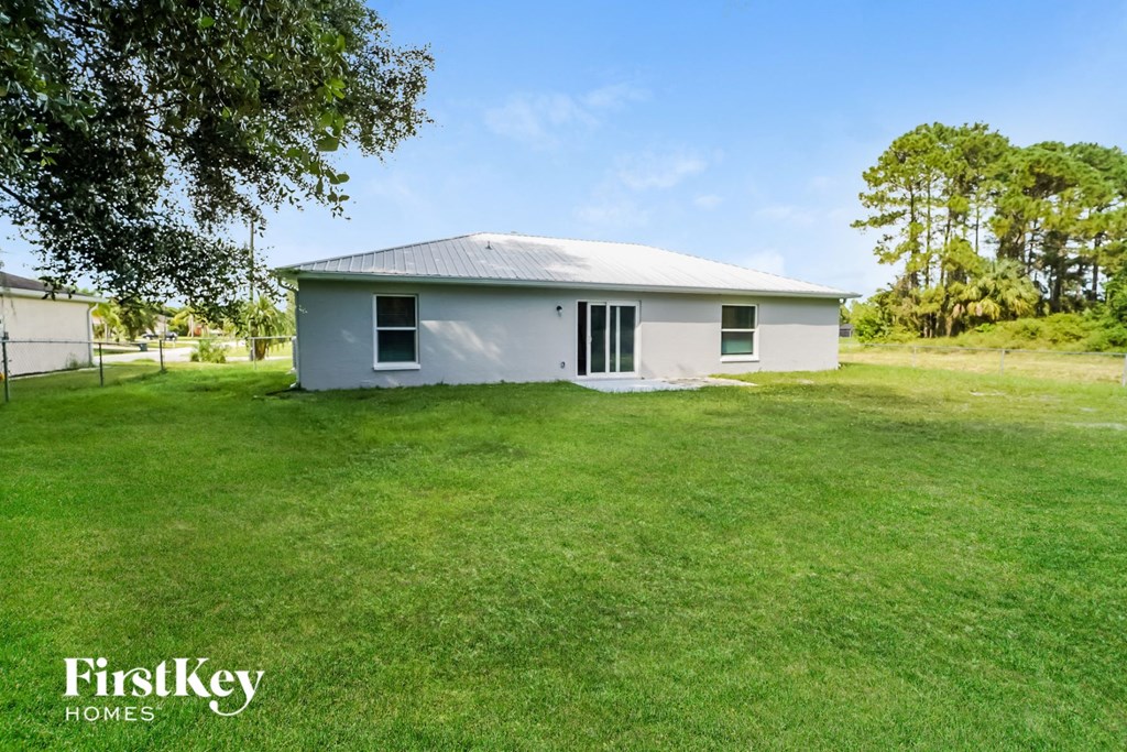 A grey house with a white roof is surrounded by a green lawn.
