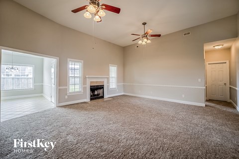 A spacious room with a fireplace and a ceiling fan.