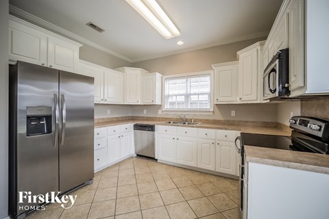 A kitchen with white cabinets and a stainless steel refrigerator.
