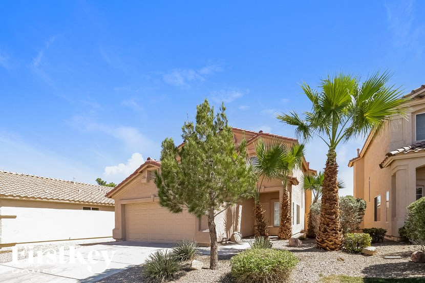 A house with a white garage door and palm trees in front.