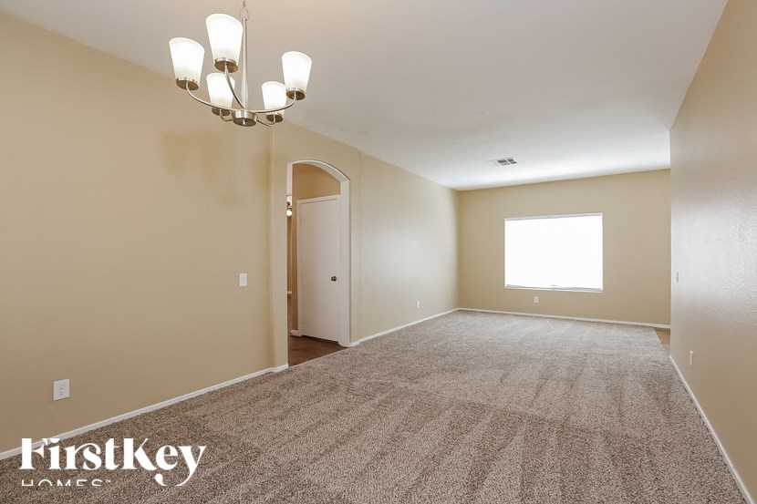 A spacious room with a carpeted floor and a chandelier hanging from the ceiling.