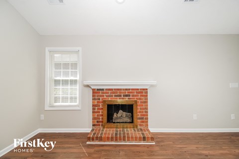 the living room has a brick fireplace and hardwood floors