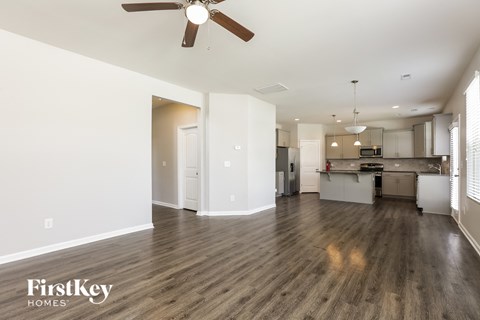 A spacious kitchen and living room with wood flooring and a ceiling fan.