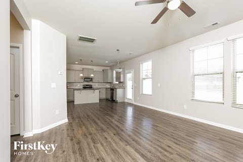 A spacious room with wooden floors and a ceiling fan.